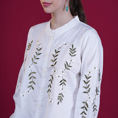 White embroidered shirt with green leaves on a red background